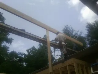 Carpenter setting a ridge beam over a new addition frame — Ice Dam Removal by Roofing Brothers in Spencerville